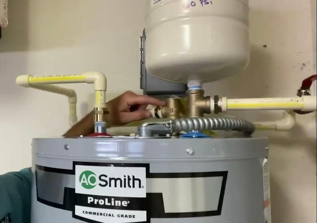 Plumber installing shutoff valve and water heater piping in residential home